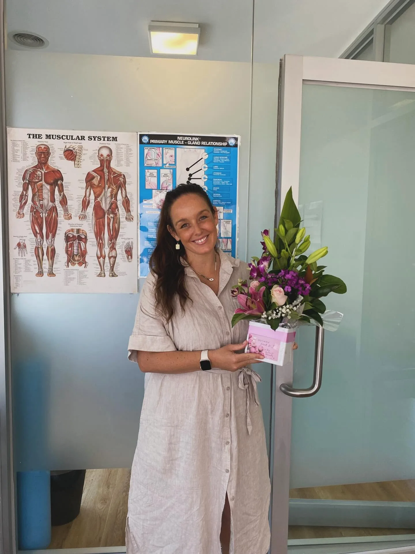 A team member in the Auburn Chiropractic treatment room beside the anatomy chart